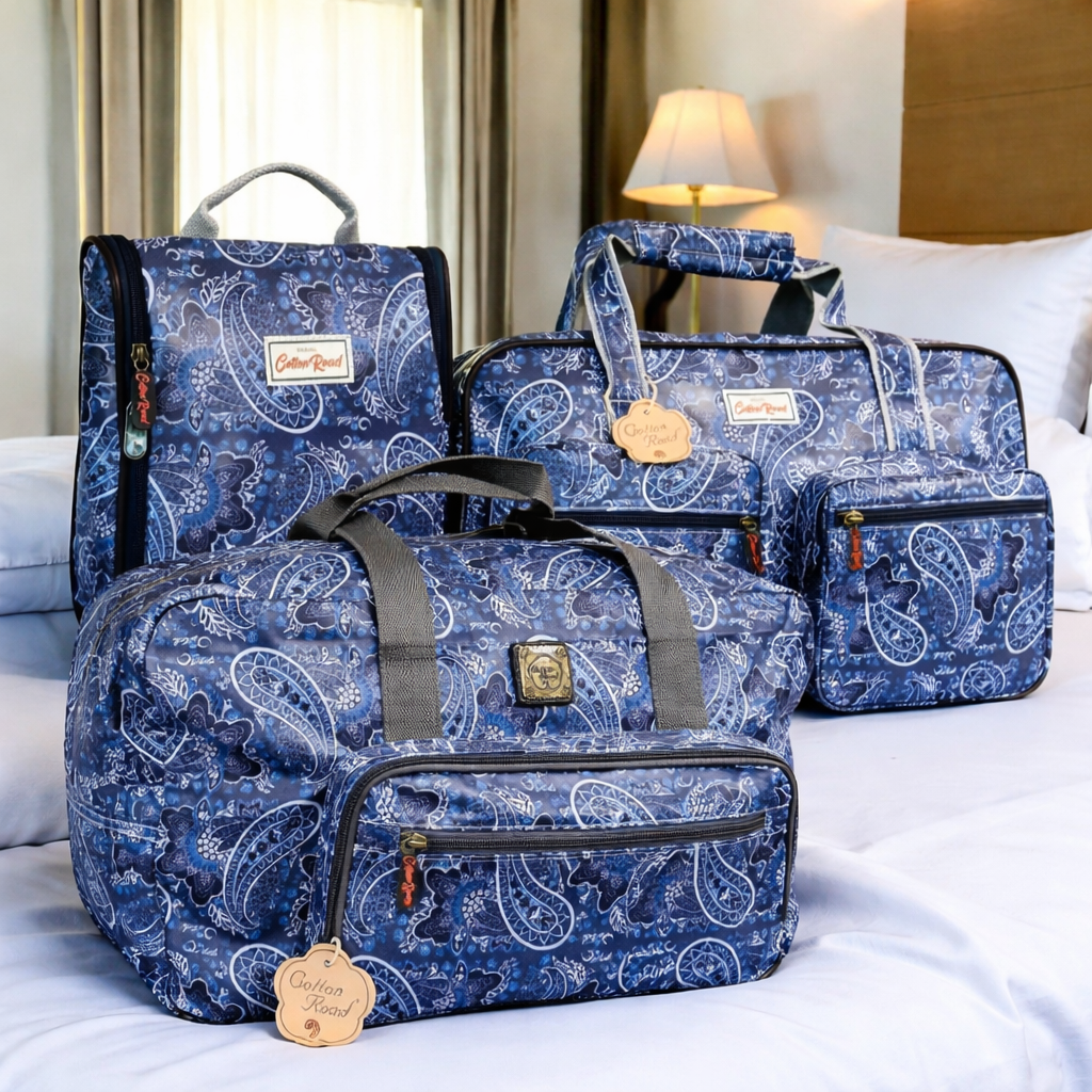 Cotton Road Blue Paisley matching travel bag set including weekender, overnight bag and hanging vanity bag in PVC on a bed in a hotel room
