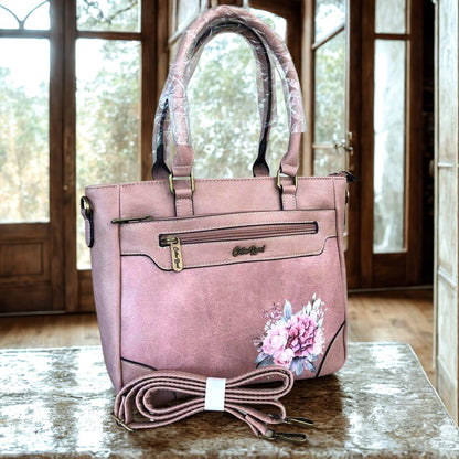 Pink pu leather Cotton Road handbag with floral design and matching carry strap on a wooden surface