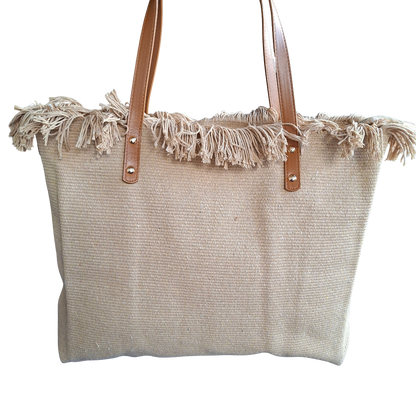 Beige woven tote bag with frayed edges and brown leather handles on a white background