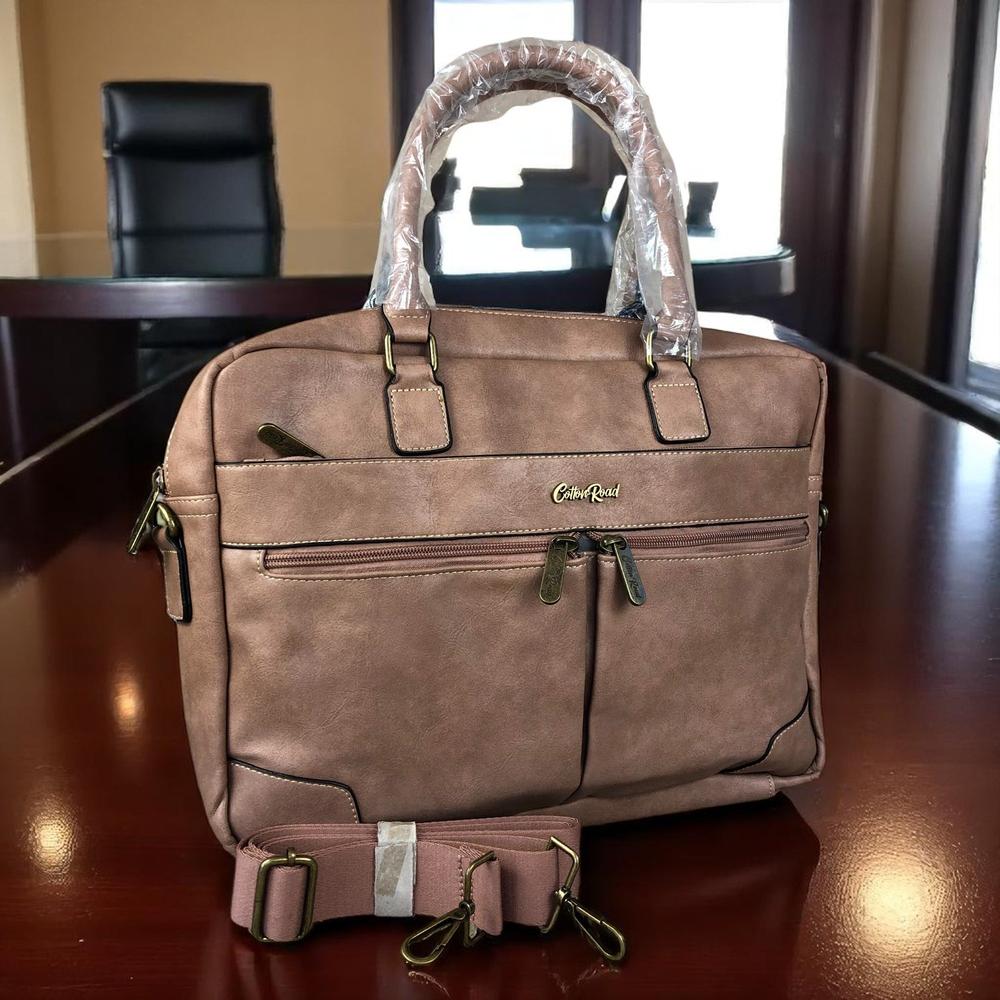 Pink PU leather laptop bag with twin handles, adjustable shoulder strap, padded compartment for 15.6" laptop, multiple zippered pockets, and trolley strap.