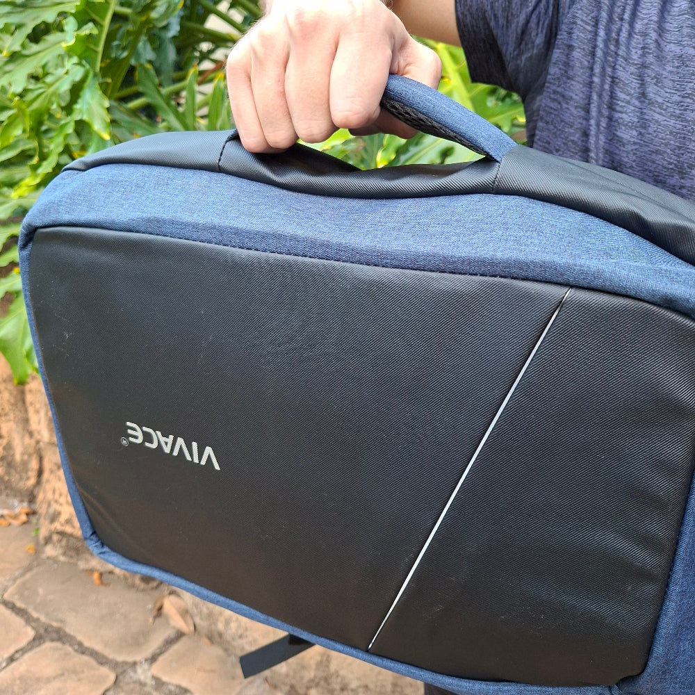 Blue and black backpack with 'VIVACE' branding held by a person on the side carry handle outdoors.