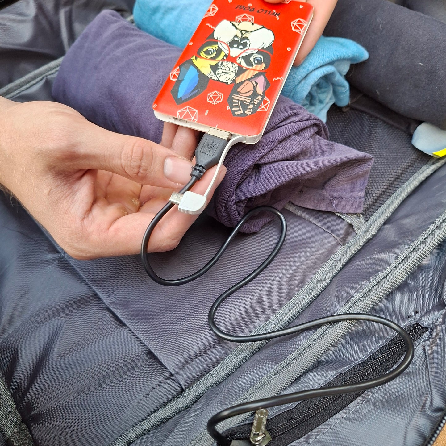 Power bank CONNECTED to USB port inside Vivace backpack in the open view.