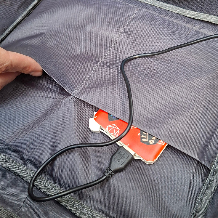Close-up of a power bank with a cable plugged into and stored snugly inside a pocket of the Vivace BLUE backpack.