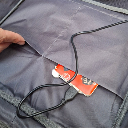 Close-up of a power bank with a cable plugged into and stored snugly inside a pocket of the Vivace BLUE backpack.