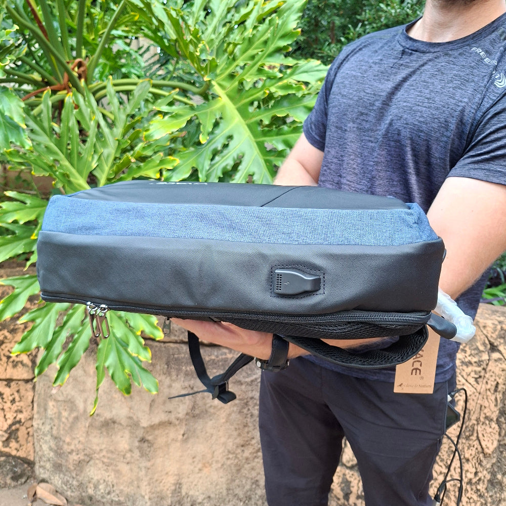 Person holding the blue/black bag VIVACE branded to show side USB port view standing outdoors.