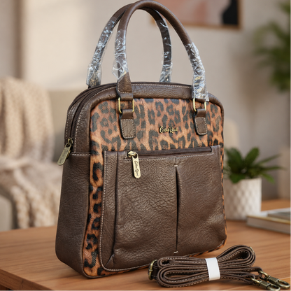 Cotton Road dark brown PU leather handbag with leopard print panels and detachable shoulder strap displayed on a wooden table in a modern indoor lifestyle setting.