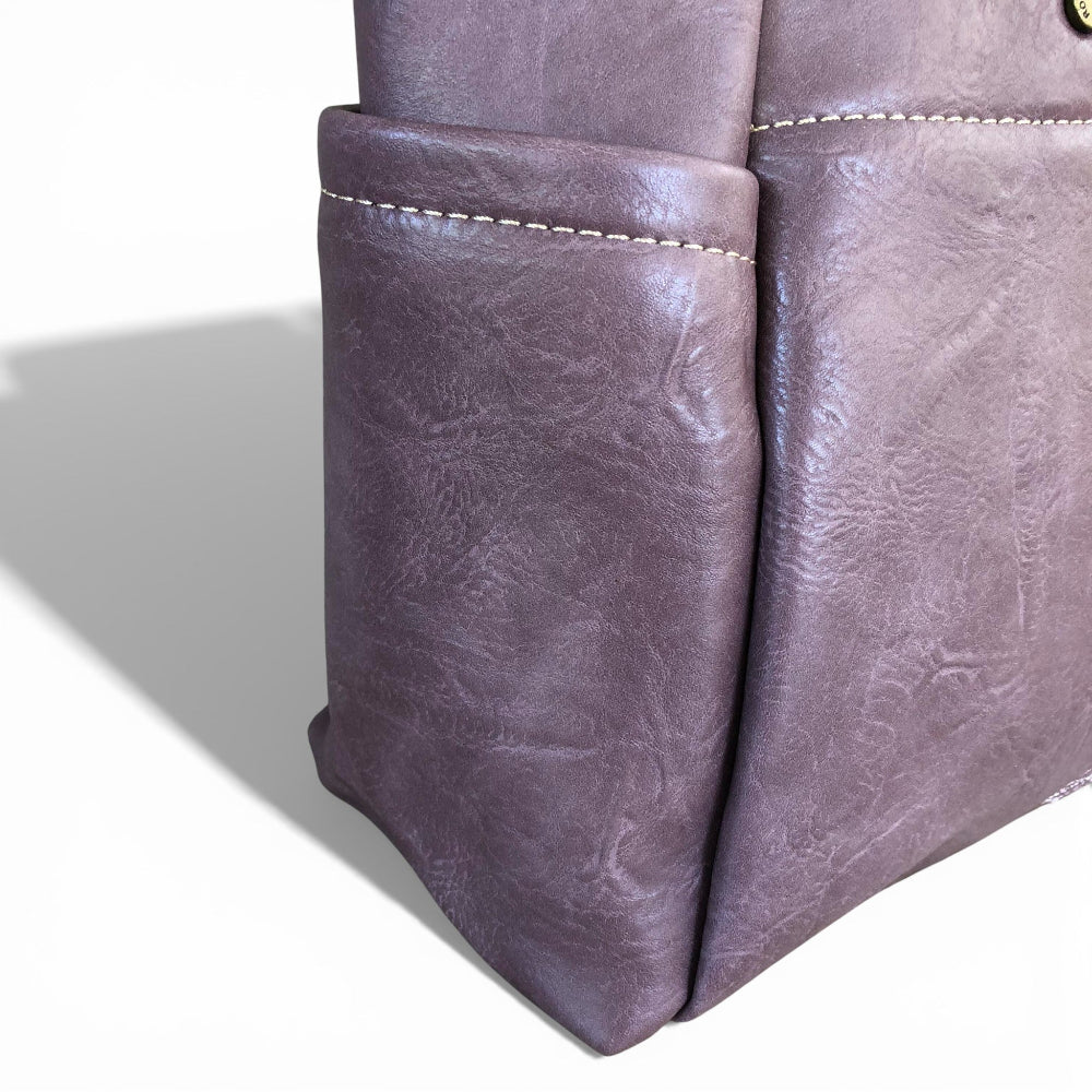 Close-up of a cotton road purple PU leather bag with visible stitching on a white background