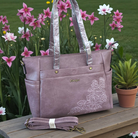 Cotton Road Purple handbag with floral design on a wooden surface with flowers in the background