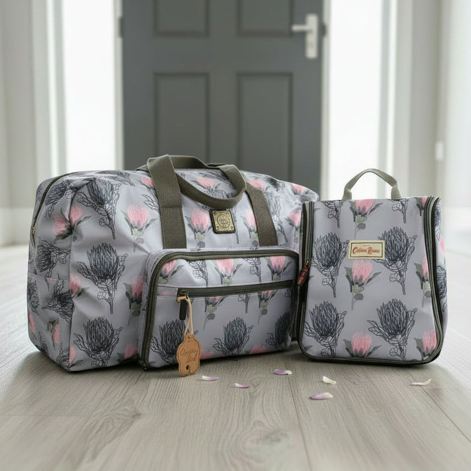 Cotton Road Matching Travel Combo Protea foldaway Weekender Bag and Vanity Bag with blue floral design on a laminated floor. Available at We Sell Bags South Africa