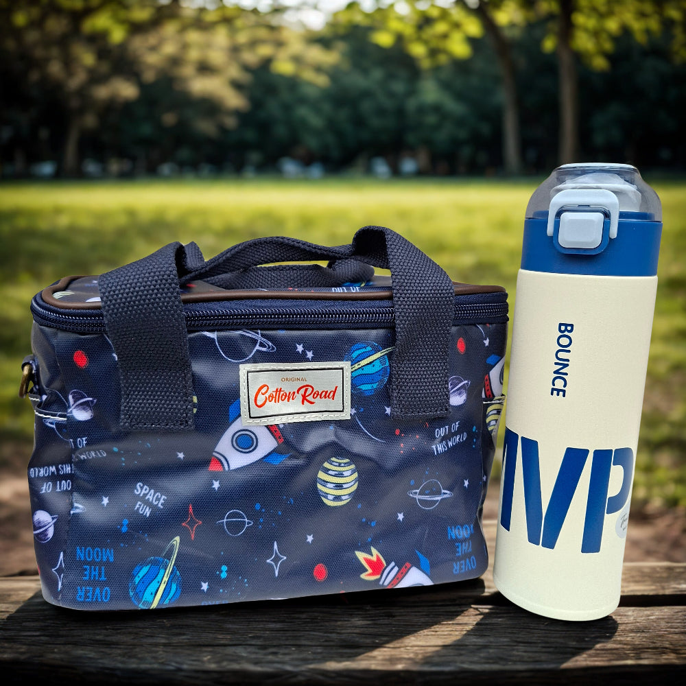Kids combo. Dark blue Insulated lunch box bag with space design and 'Bounce' thermal water bottle on a park bench